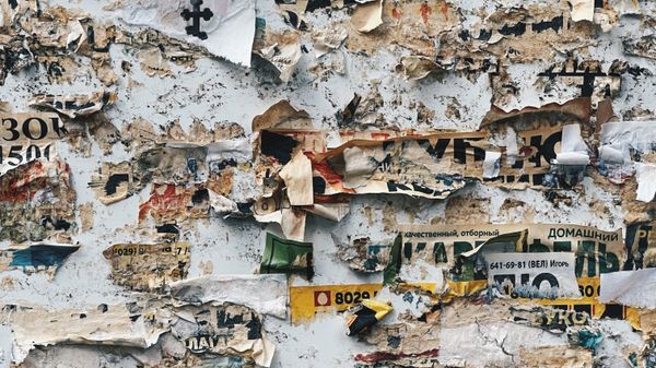 Wall covered with torn remnants of posters showing bits of Cyrilic writing